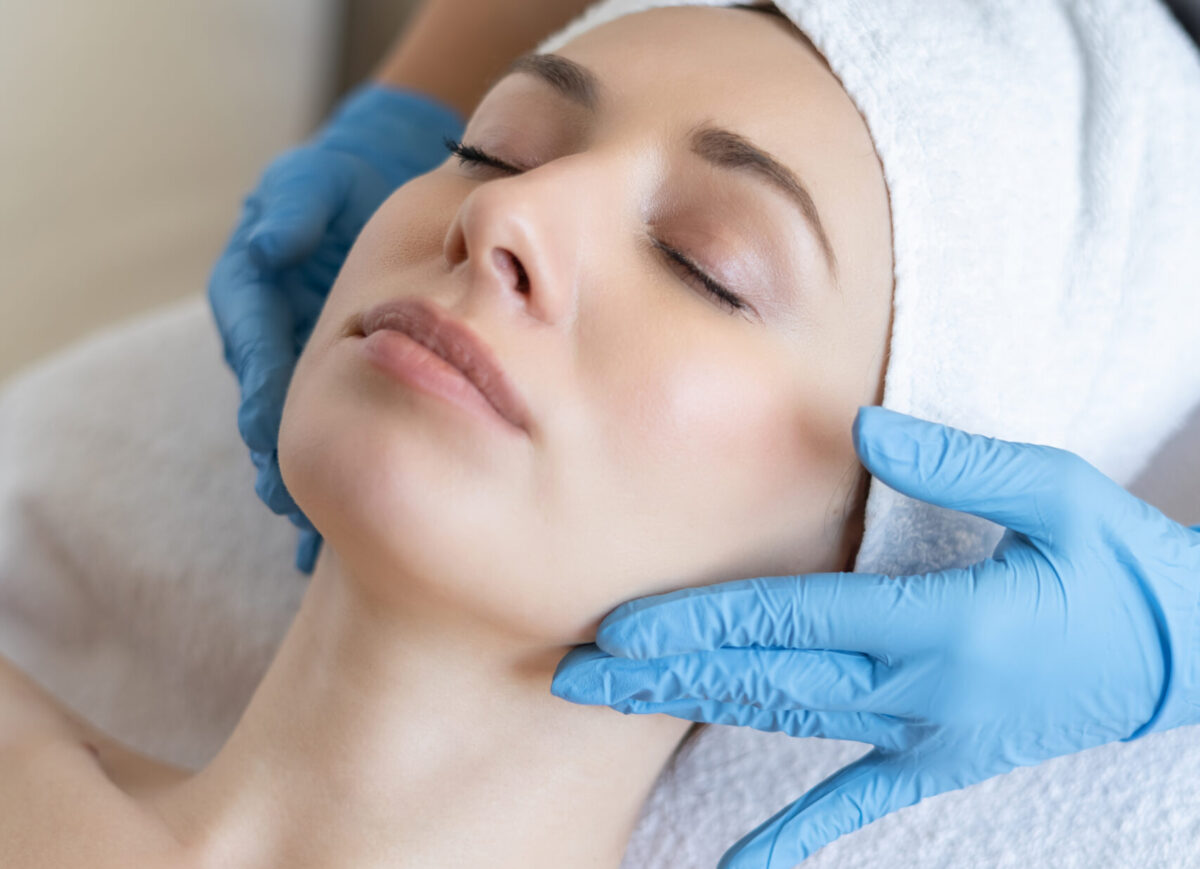 A young beautiful girl lies on the table at the beautician and receives procedures, a light massage, hands in blue gloves, the skin is smooth
